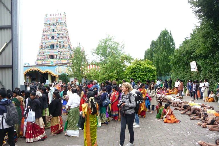 Ein Tempelfest in Hamm. Eine Menschenmenge von Menschen mit südasiatischem Migrationshintergrund. Im Vordergrund steht eine Person mit einer Fotokamera in der Hand. Tempelfest (2018) des hindu-tamilischen Sri Kamadchi Ampal Tempel in Hamm/Uentrop.